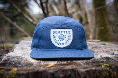 Navy blue raincloud Seattle Hat on a tree stump